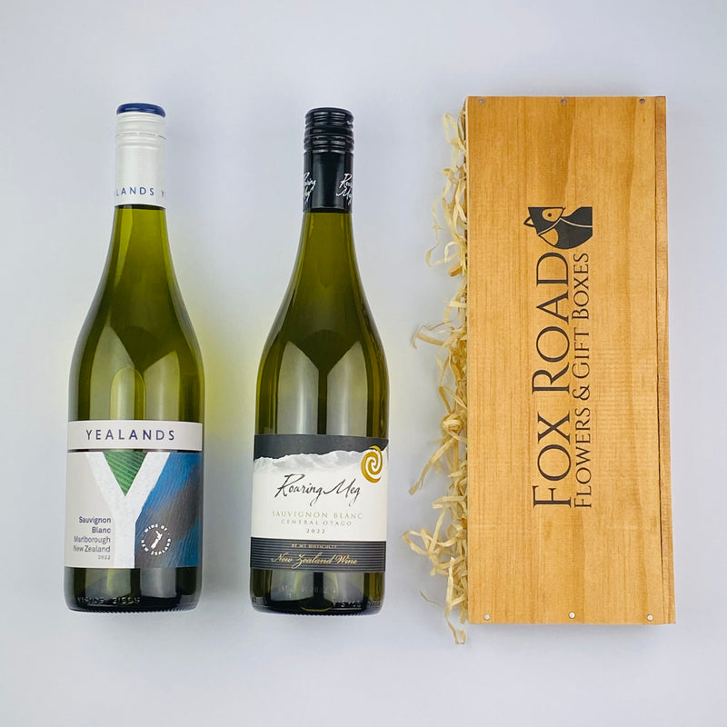Two bottles of New Zealand Sauvignon Blanc next to wooden gift hamper