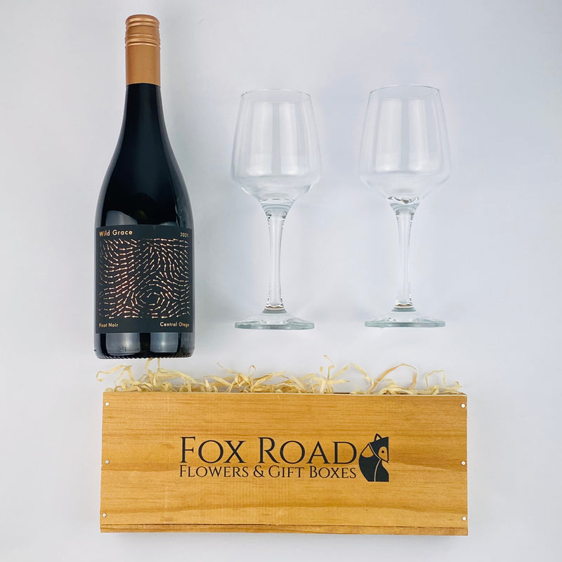 Wild Grace wine with wine glasses besides wooden gift crate