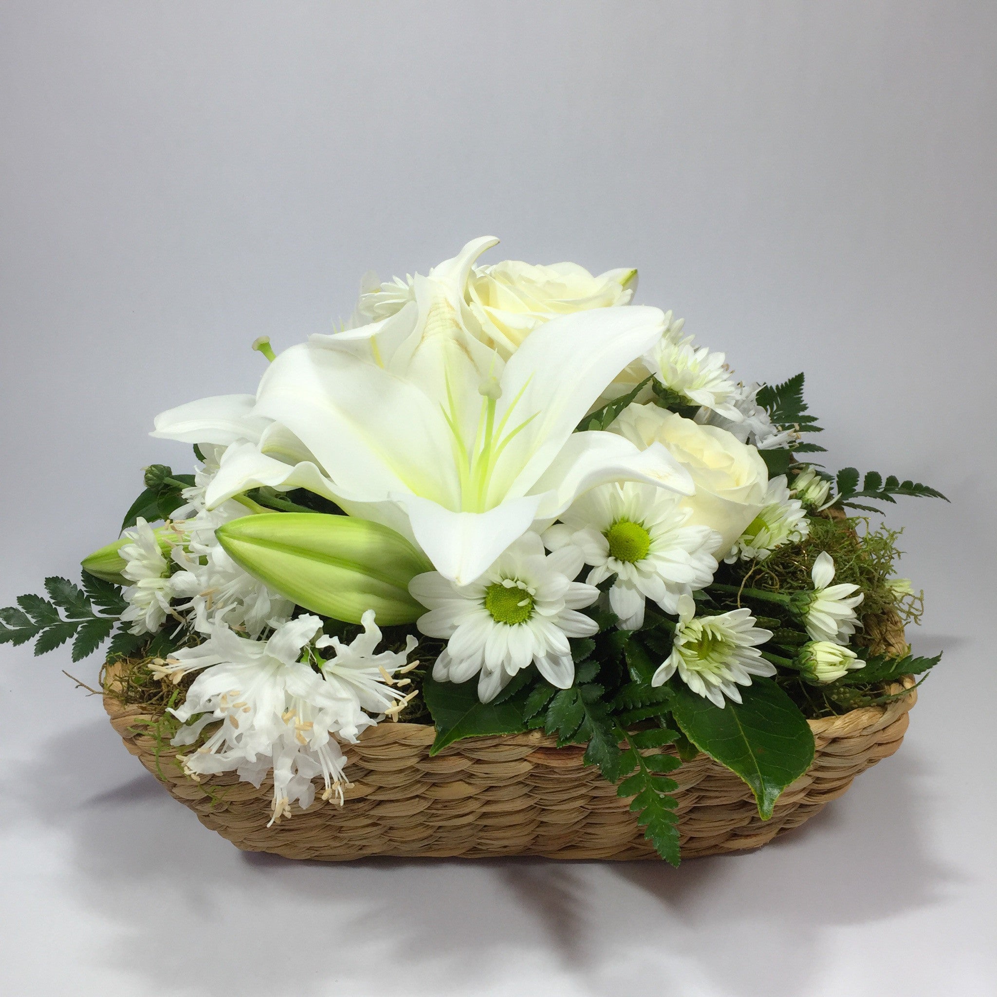 Wicker basket with lilies and other funeral flowers