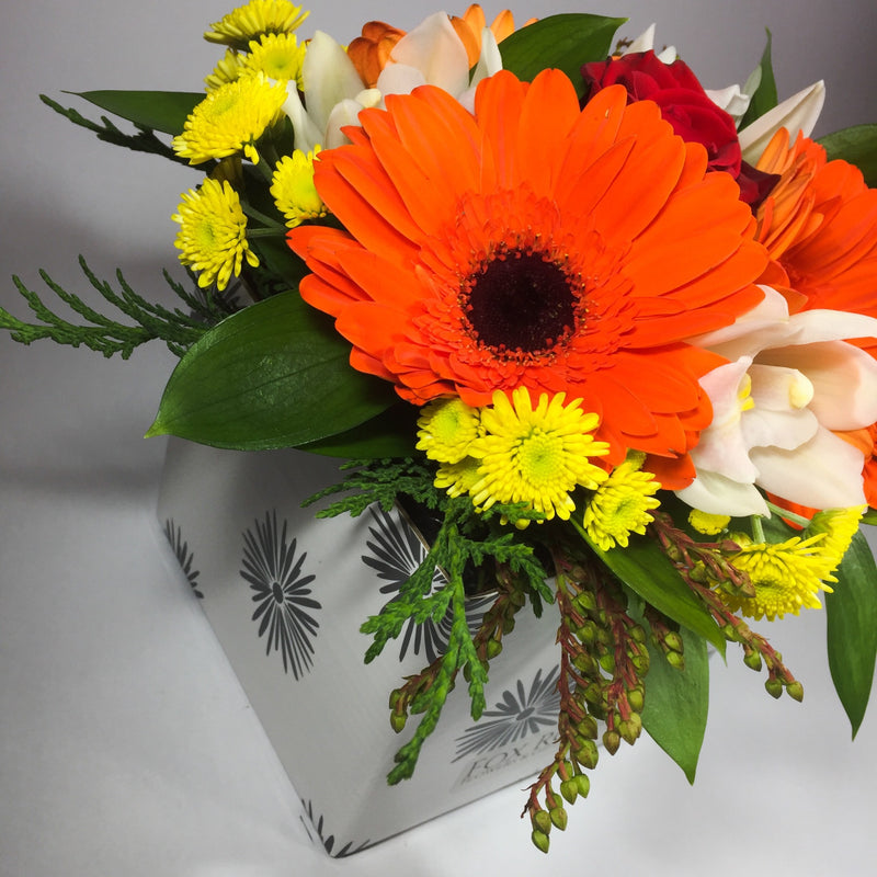 Bright flowers in a birthday box with greenery