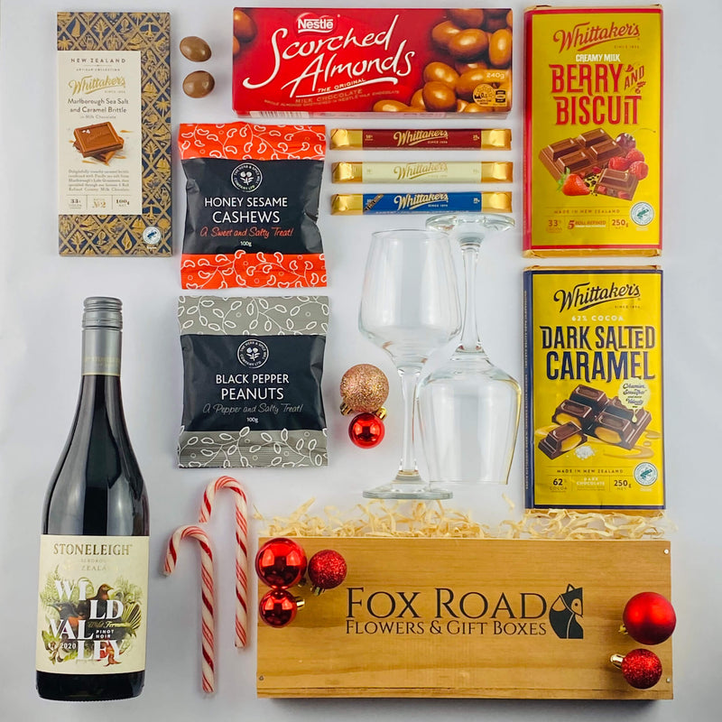 Christmas gift hamper with wine and nuts and wine glasses.